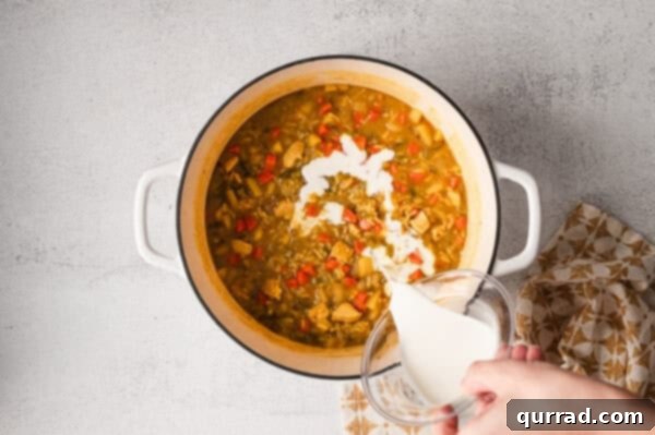 Adding a splash of heavy cream to the finished soup in a stock pot, creating a rich and creamy texture.