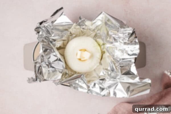 A raw onion with butter in the center in foil