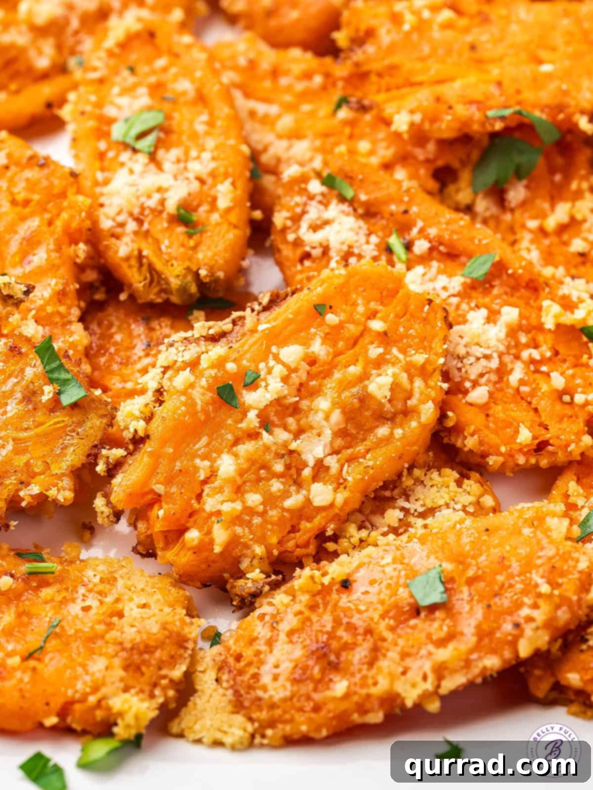 Close up of golden-brown parmesan smashed carrots on a baking sheet, showcasing their crispy texture
