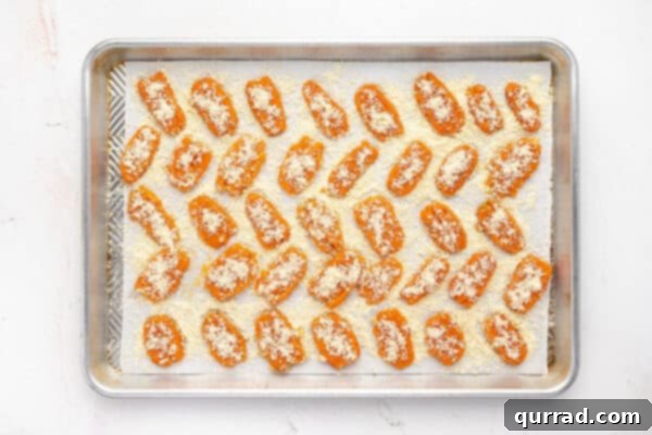 Unbaked parmesan smashed carrots on a baking sheet before going into the oven