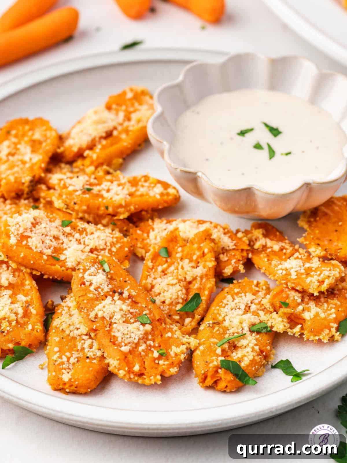 Smashed carrots served on a white plate with a small bowl of ranch dressing for dipping