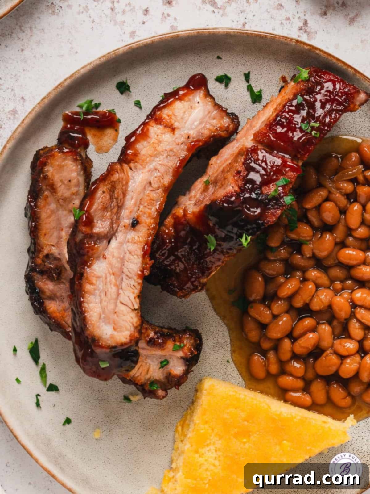 Fall-Off-The-Bone Baked Ribs 4 A plate featuring delicious baked baby back ribs served alongside a generous portion of classic baked beans, ready for a comforting meal.