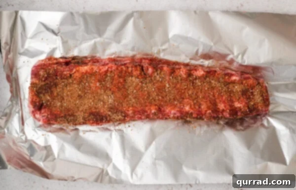 Fall-Off-The-Bone Baked Ribs 8 A rack of ribs coated with a spice rub on a piece of foil