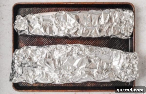 Fall-Off-The-Bone Baked Ribs 9 Two racks of ribs in foil on a baking sheet
