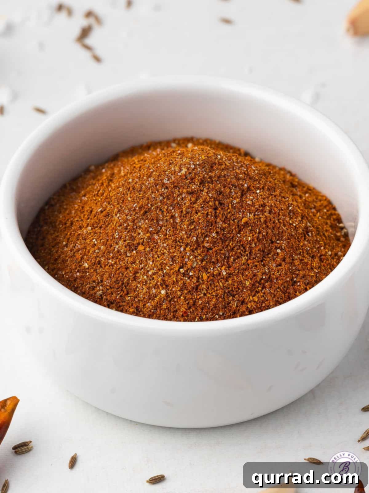 A white bowl of homemade chili seasoning, showcasing its rich reddish-brown color and fine texture