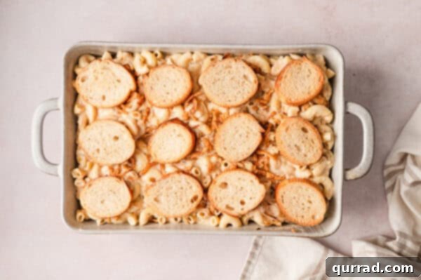 French Onion Macaroni Gratin 14 Toasted baguette slices placed on top of french onion mac and cheese in a baking dish.
