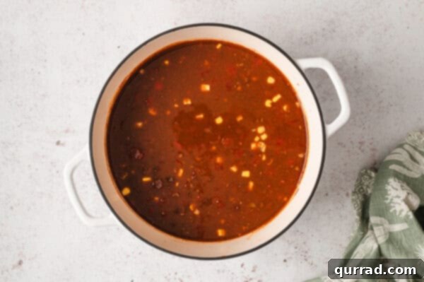 Broth added to soup ingredients in a pot, simmering