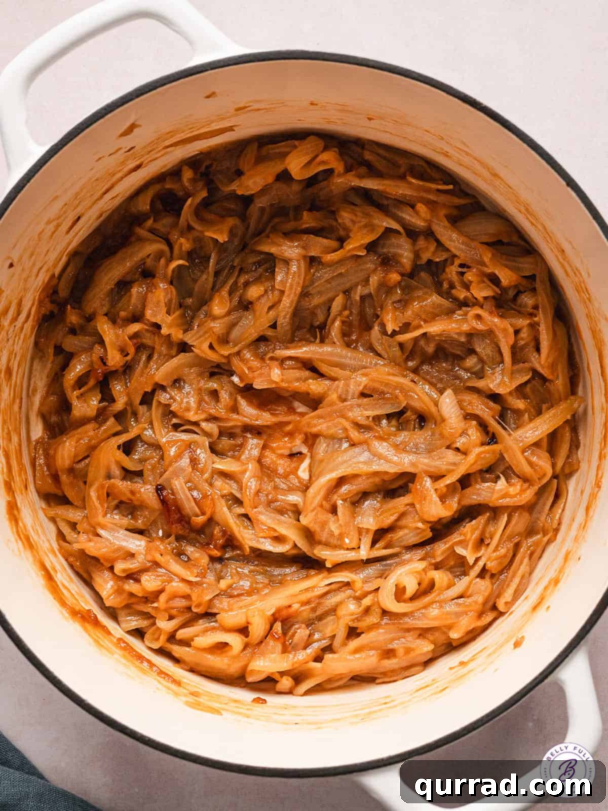 A large pot of sweet onions slowly caramelizing, ready to become a rich and flavorful condiment. An overhead view of a large pot filled with thinly sliced onions, slowly caramelizing to a deep golden-brown hue.