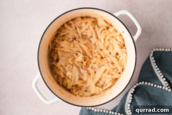 Sliced onions slowly caramelizing in a pot, turning a rich golden-brown color.