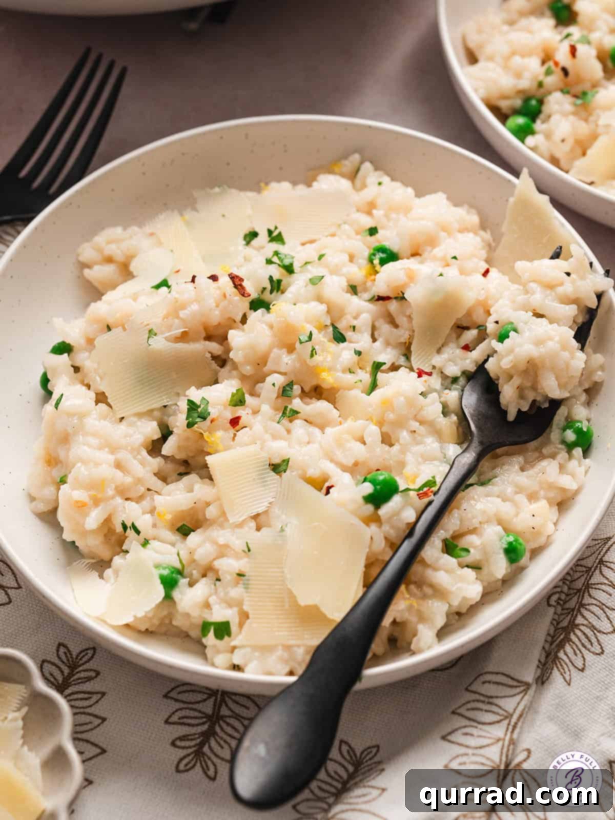 Creamy and Hearty Baked Risotto with Fresh Garnish A black spoon in a full bowl of baked risotto, garnished with fresh herbs and shaved Parmesan.