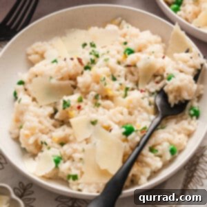 A black spoon in a bowl of creamy baked risotto, ready to be served.