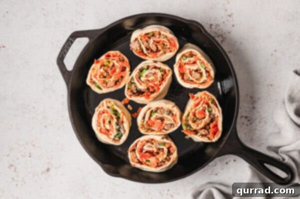 Overhead view of unbaked pizza rolls in a cast iron skillet
