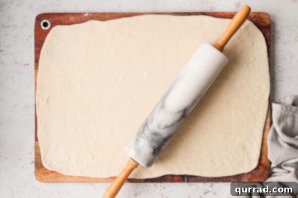 Rolling pin rolling pizza dough into a rectangle