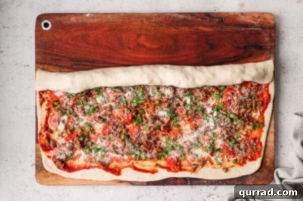 Rolling a rectangle of pizza dough into a log