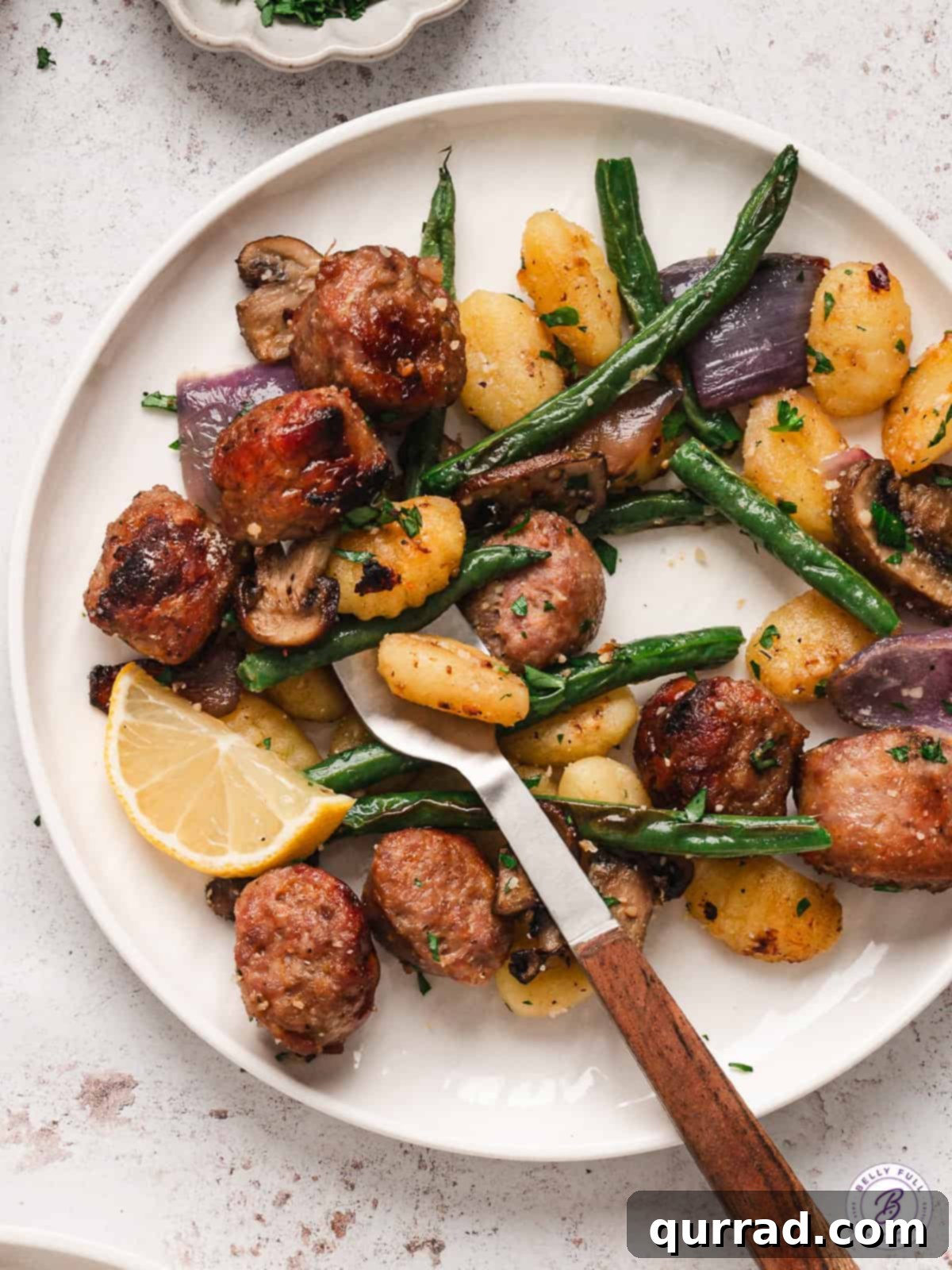 This Sheet Pan Gnocchi and Sausage is loaded with veggies and perfectly seasoned for an easy weeknight dinner the entire family will love. Gnocchi, sausage, and veggies on a white plate, showcasing a delicious meal