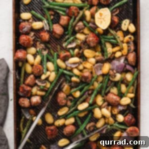 Tongs on a sheet pan of sausage and gnocchi