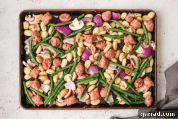 One Pan Gnocchi and Sausage Dinner 3 Gnocchi, Italian sausage, green beans, mushrooms, and onion on a sheet pan ready for roasting