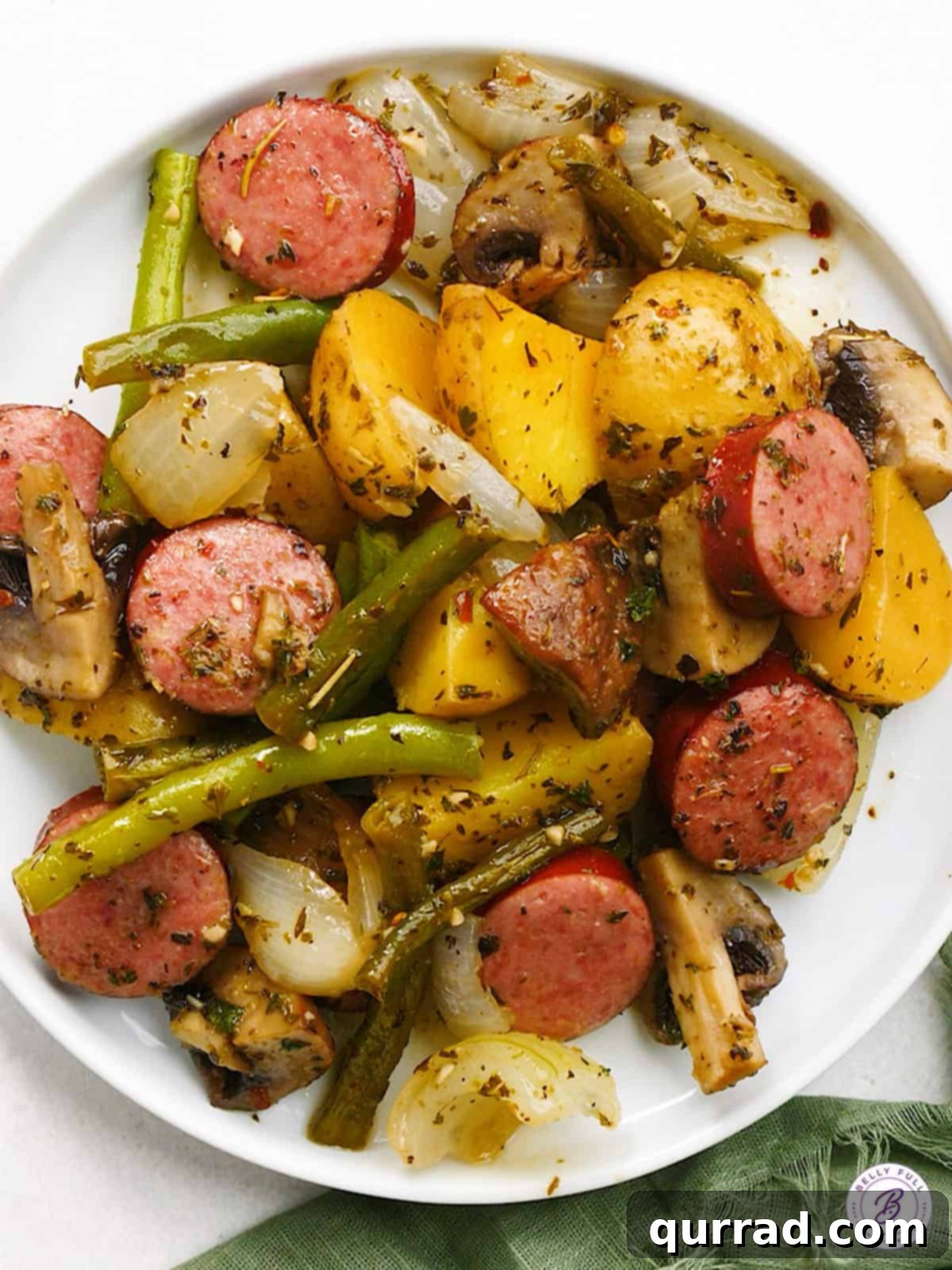 A single serving of Kielbasa and Veggie Casserole plated beautifully, showcasing the golden-brown kielbasa, tender mushrooms, green beans, and roasted potatoes.