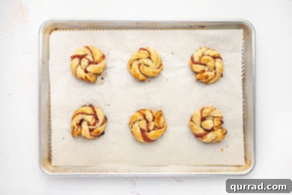 Puff Pastry Jam Spirals 8 Baked jam puff pastry rolls on a baking sheet