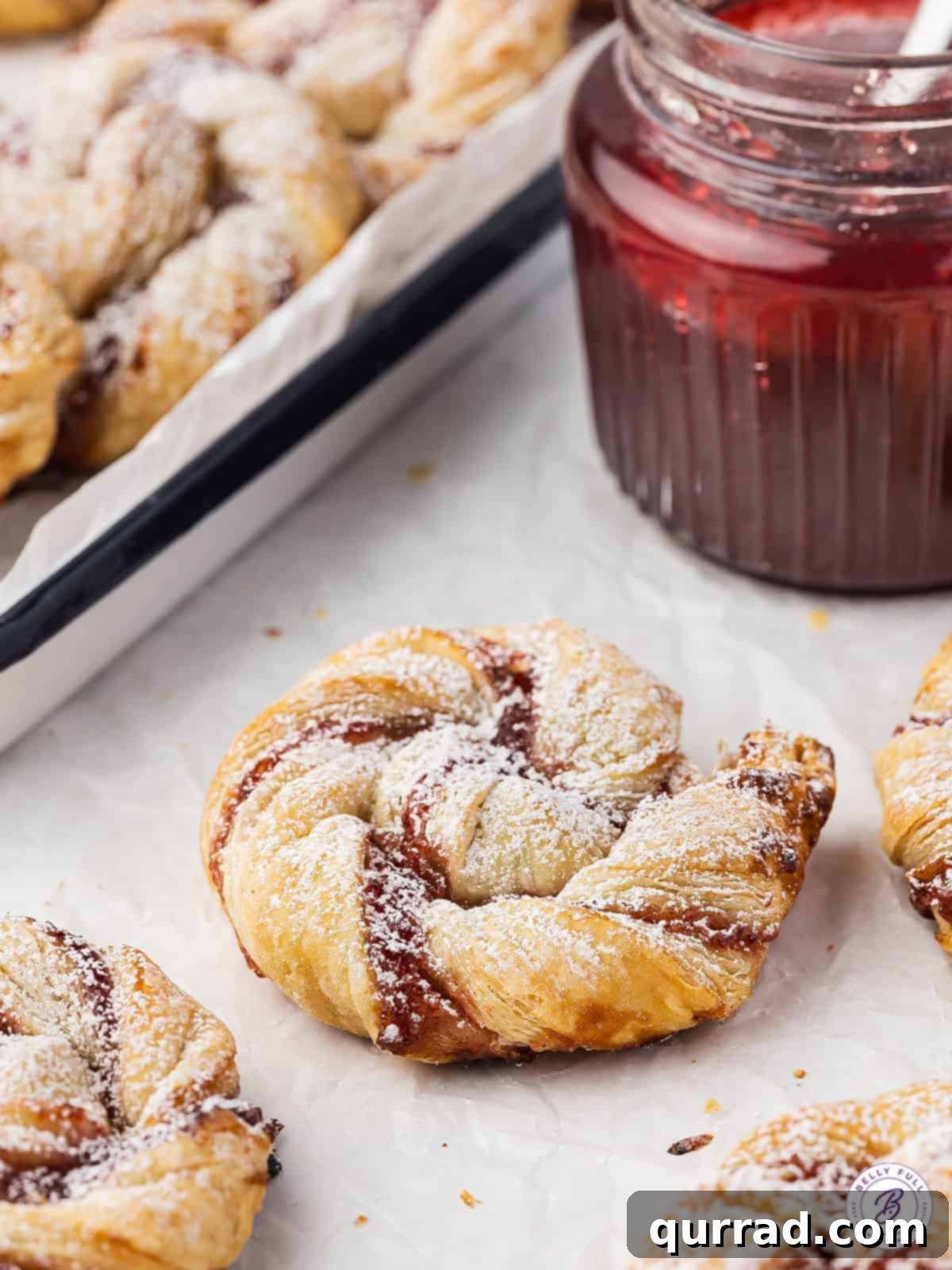 Simple Jam Puff Pastry Rolls - A delightful treat! Jam puff pastry rolls on a baking sheet, ready to be dusted with powdered sugar