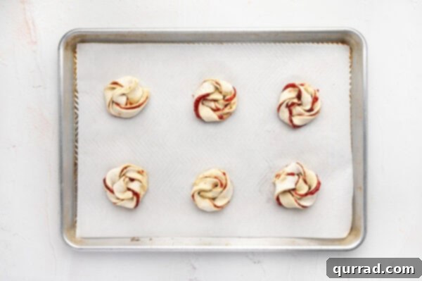 Puff Pastry Jam Spirals 7 Unbaked jam puff pastry rolls on a baking sheet