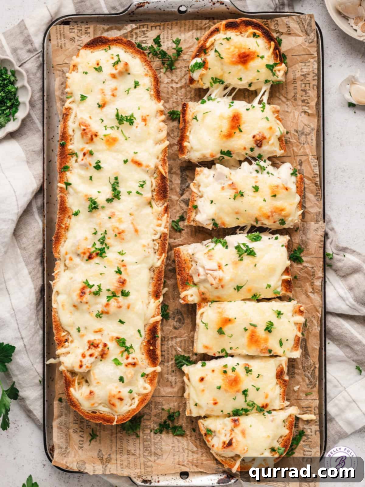Freshly baked Chicken Alfredo French Bread Pizza, ready to delight. Two chicken alfredo French bread pizzas on a wooden cutting board, one whole and one cut into perfect slices, garnished with fresh parsley.