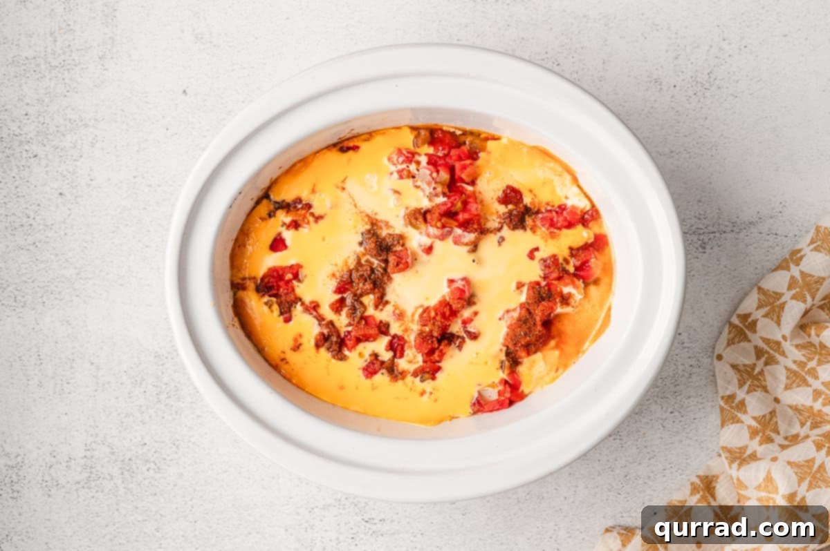 Melted Rotel and cheese dip in a crockpot, stirred until smooth and creamy.