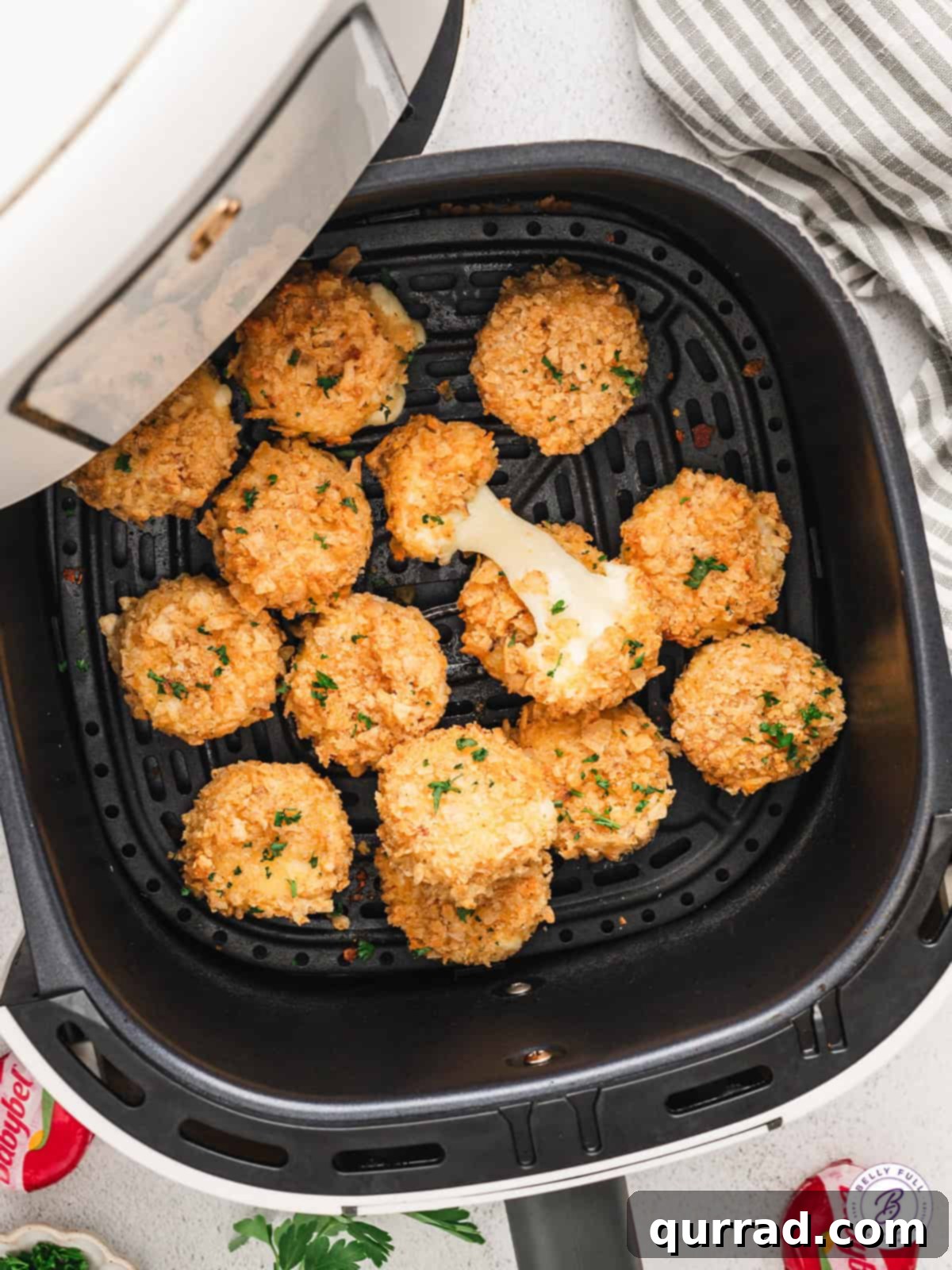 Golden brown and incredibly gooey, Air Fried Babybel Cheese is the ultimate crispy snack or appetizer. Two pieces of air fried babybel cheese, golden and melted, on a small wooden board