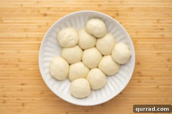 Dough divided into 12 equal pieces, arranged on a surface.
