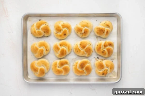 Freshly baked, golden brown garlic knots on a baking sheet, hot from the oven.