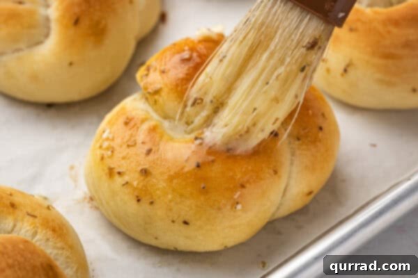 Warm garlic knots being brushed with melted garlic butter after baking.