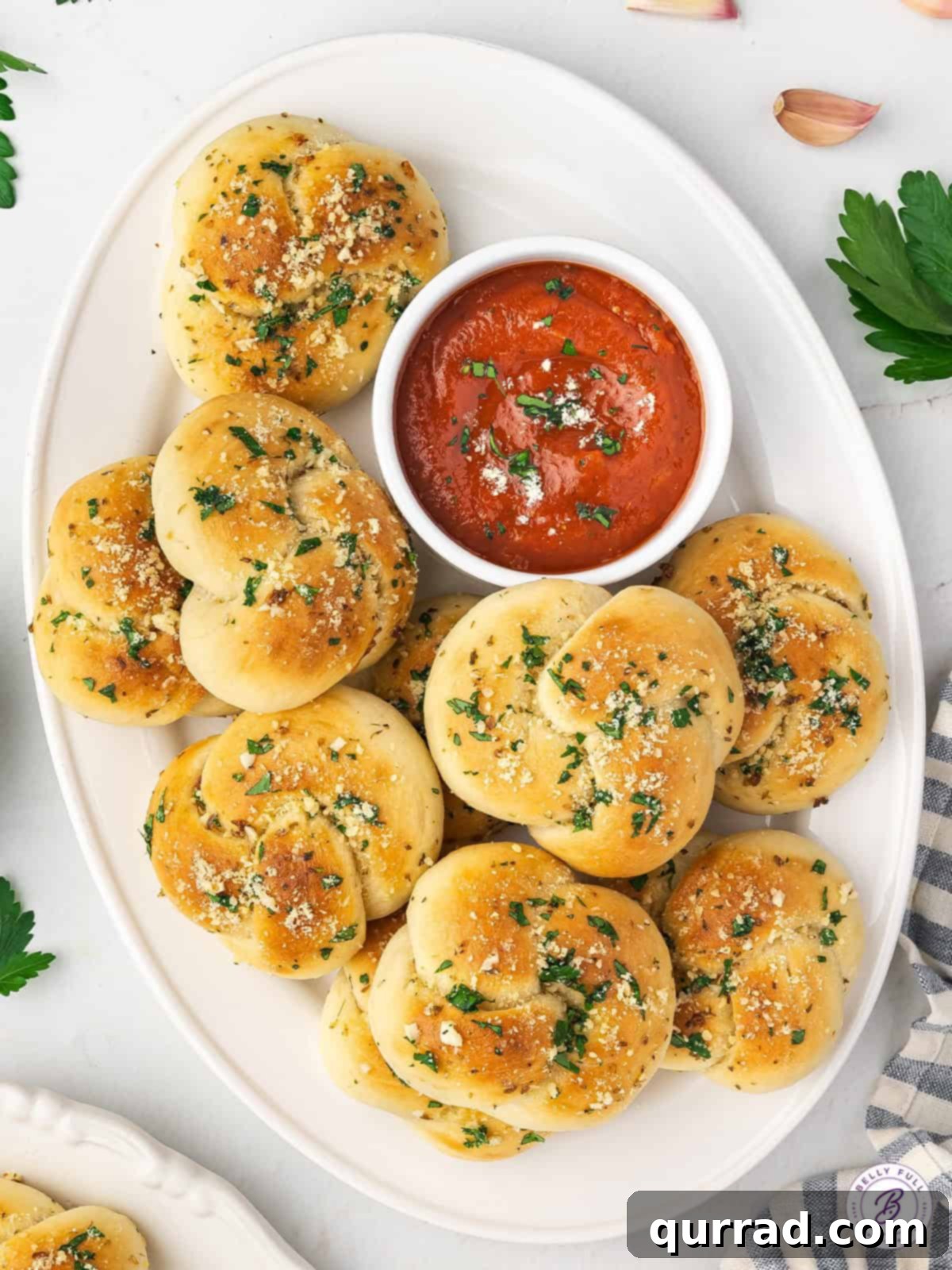 Overhead view of a beautifully arranged plate of homemade garlic knots, accompanied by a small bowl of rich marinara sauce, perfect for dipping.