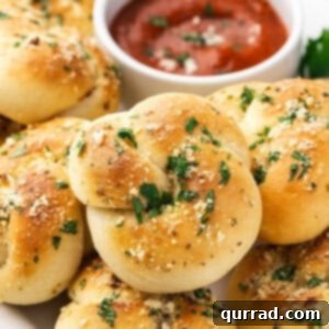 Close up of a garlic knot on a plate with marinara for dipping.