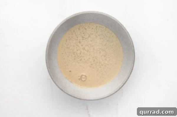 Active dry yeast blooming in warm water with sugar, showing froth on top.