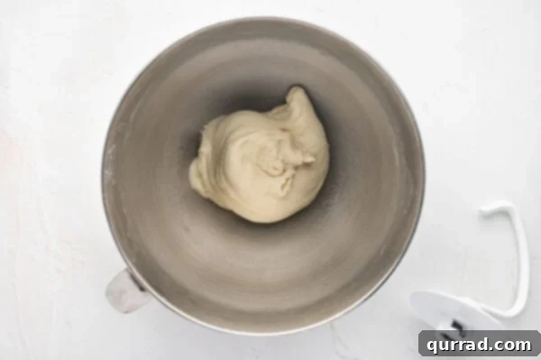 Smooth and elastic dough being kneaded by a dough hook in a stand mixer.