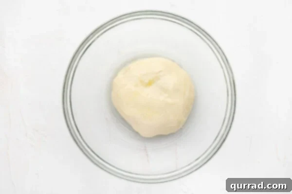 A smooth ball of dough placed in an olive oil-coated glass bowl, ready for rising.