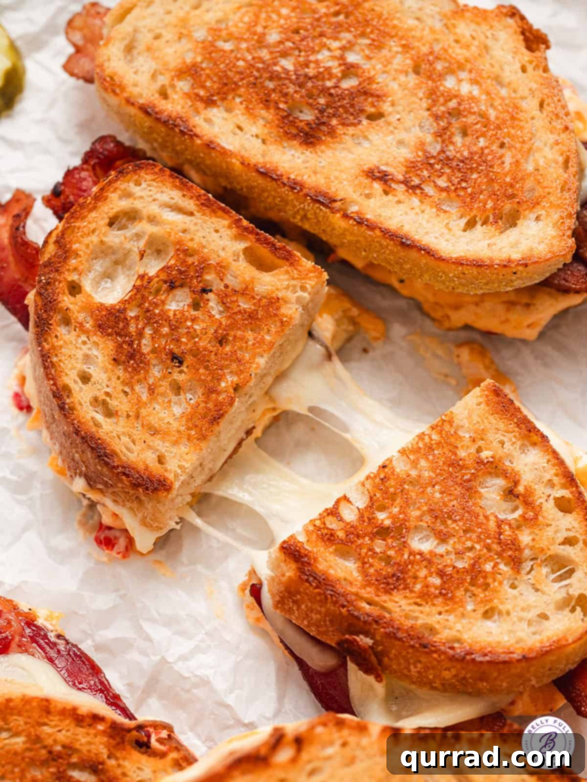 A perfectly halved Pimento Grilled Cheese sandwich, showcasing its creamy pimento cheese, melty provolone, and crispy bacon between golden sourdough slices.