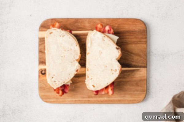 Two pimento grilled cheese sandwiches buttered on the outside, ready for grilling on a cutting board.