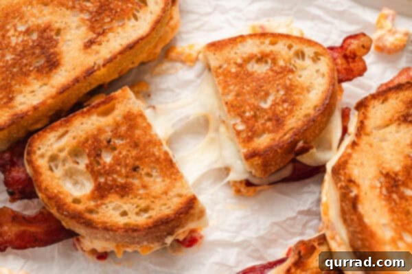 A pimento grilled cheese sandwich cut in half, revealing the layers of melted cheese and bacon, ready to be enjoyed.
