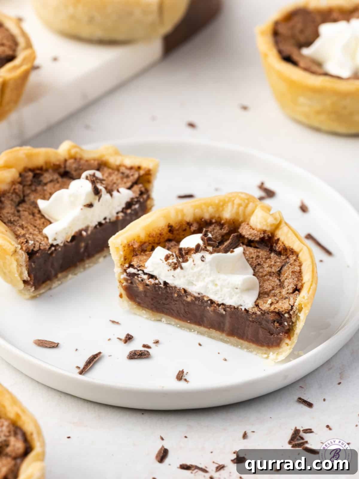 These Mini Chocolate Pies are smooth and creamy with a rich chocolate flavor. The perfect serving size, these are great for parties! A mini chocolate pie on a plate cut in half