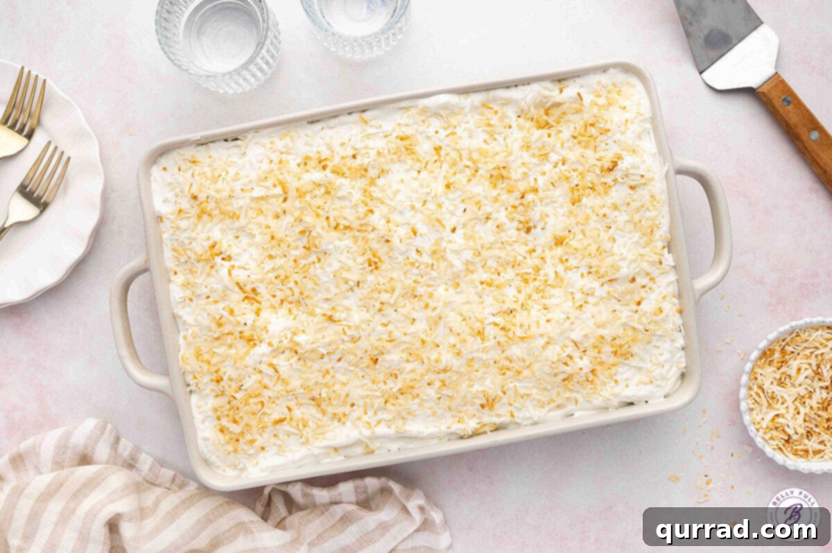 Tropical Coconut Dream Cake 14 The fully assembled and uncut coconut cake resting in its casserole dish, with a generous layer of white frosting and a golden sprinkle of toasted coconut flakes.
