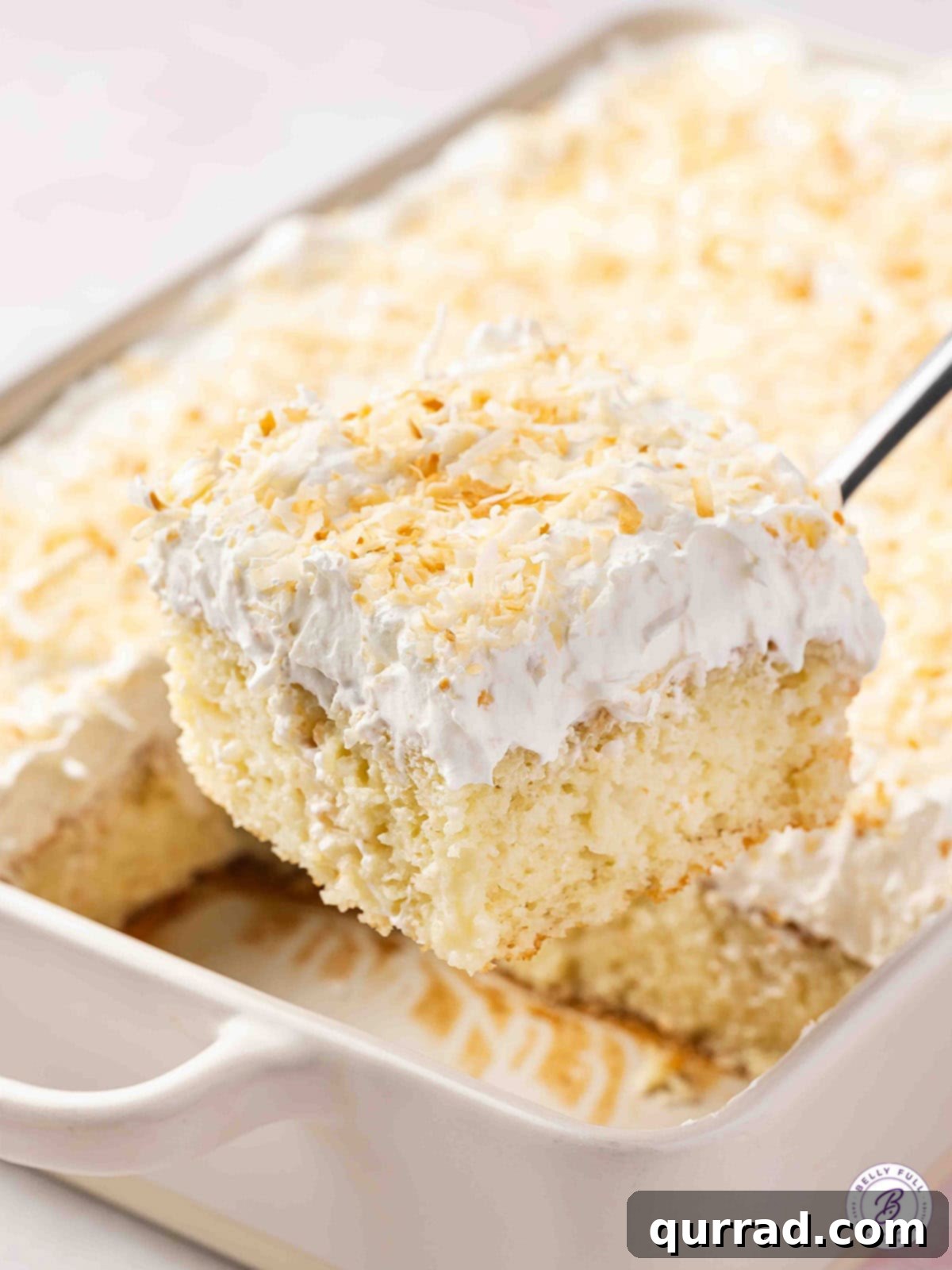 Tropical Coconut Dream Cake 15 A delicious slice of frosted coconut cake being lifted from the pan with a serving spatula, ready to be enjoyed.
