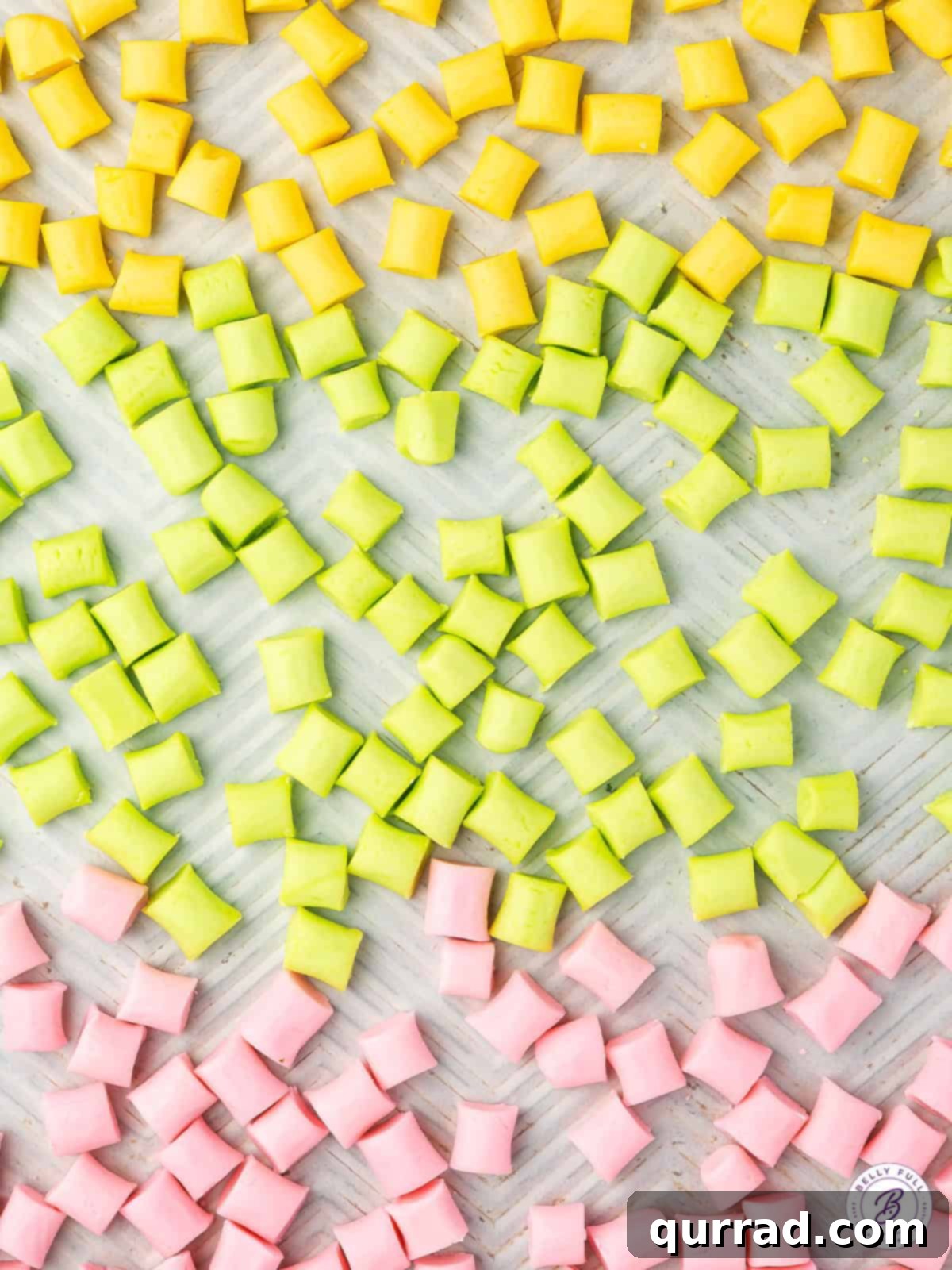 An overhead shot of vibrant orange, green, and pink butter mints neatly arranged, highlighting their appealing colors.