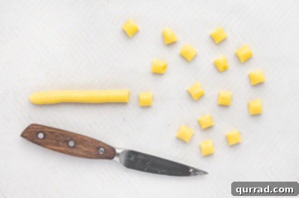 Yellow butter mint dough being cut into small, uniform pieces on a cutting board
