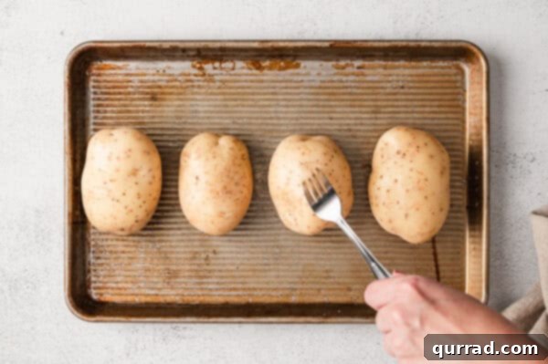 Loaded Baked Potato Delights 4 A fork pricking holes into 4 potatoes on a baking sheet.