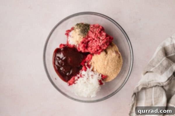 Ground beef, seasonings, breadcrumbs, and BBQ sauce in a bowl, ready to be mixed