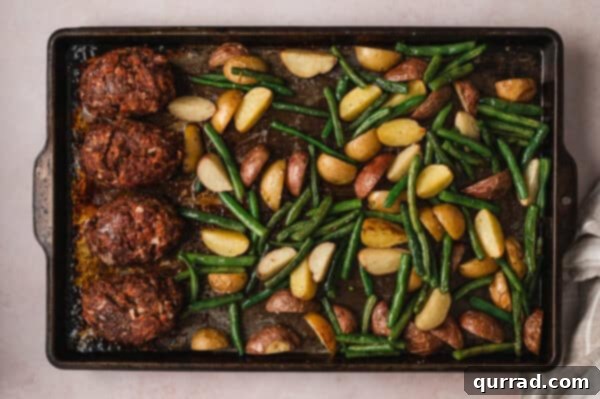 Overhead view of sheet pan mini meatloaves, green beans, and potatoes after baking