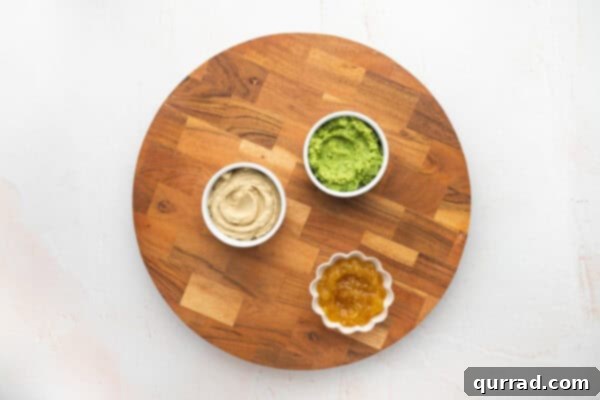 Hummus, guacamole, and marmalade in small bowls on a charcuterie board base