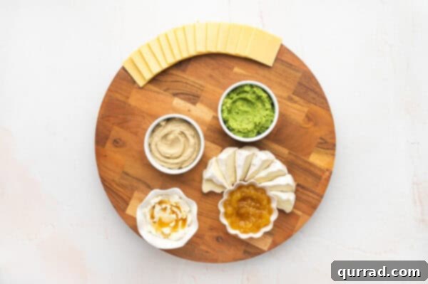 Various cheeses like goat cheese, brie, and gouda arranged on the charcuterie board
