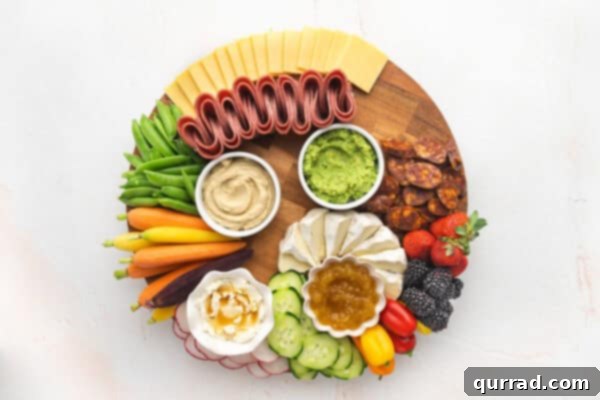 Charcuterie board showing arrangement of fresh produce, dips, cheeses, and meats